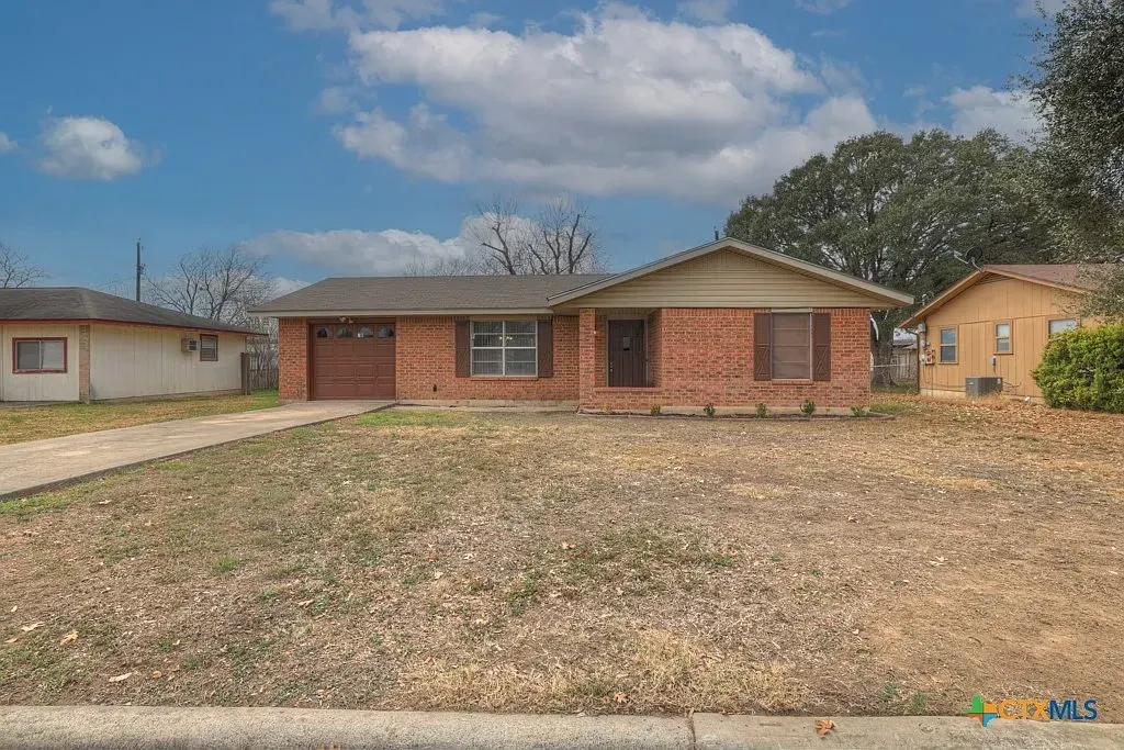 Front of the Gruene Road Residence, a single-story red-brick home with a front lawn and a driveway to the garage.